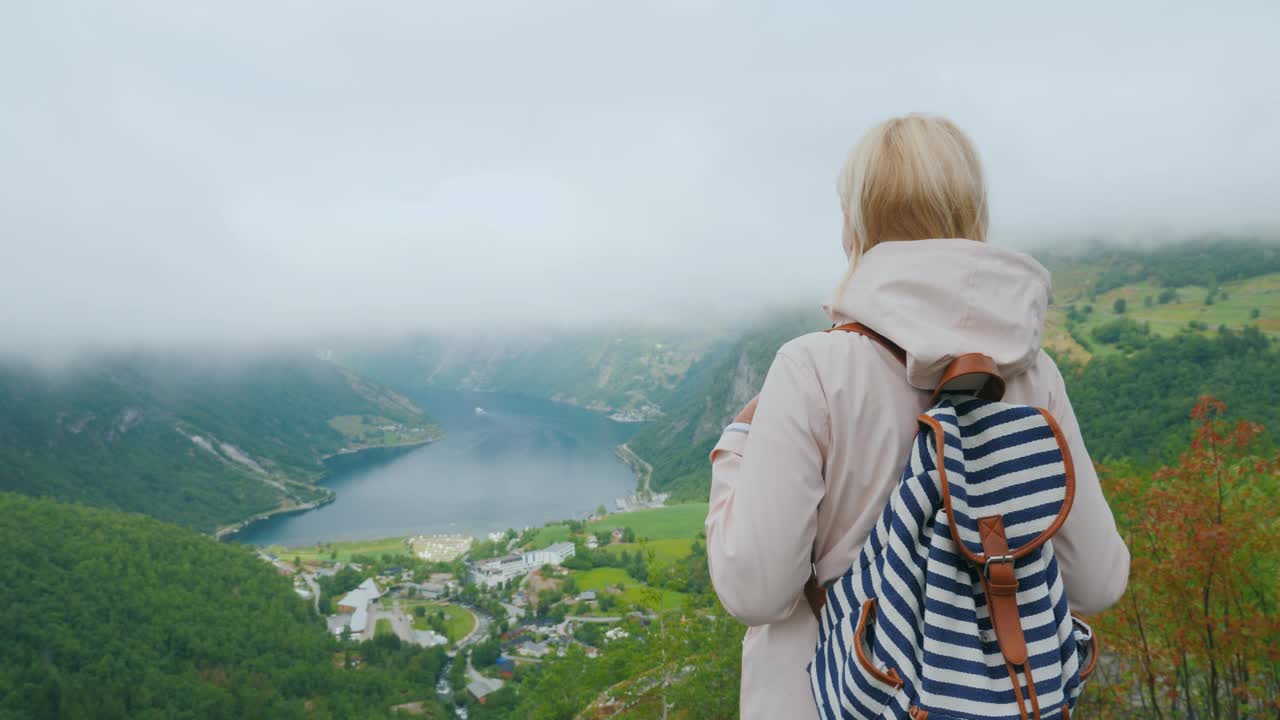 一个背着背包的女人在欣赏峡湾的美景。从挪威著名的飞石上俯瞰视频下载