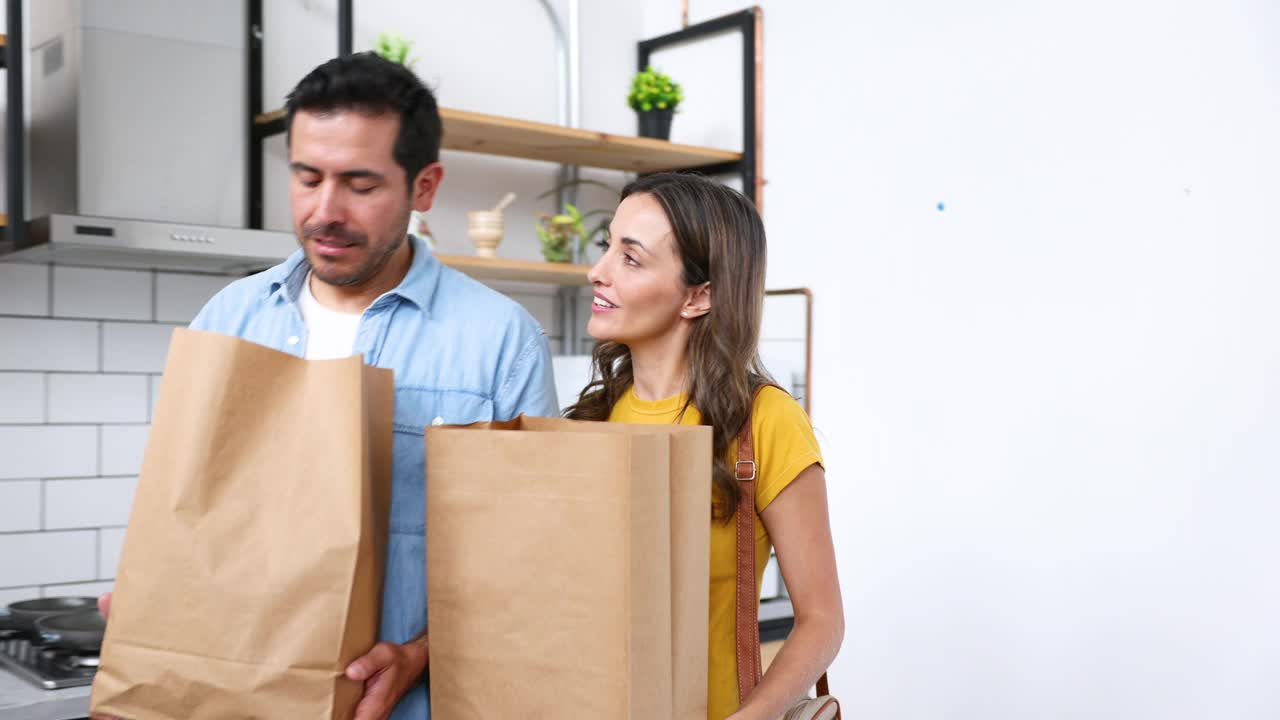 一对夫妇从超市回家，一边聊天一边打开杂货的包装视频下载