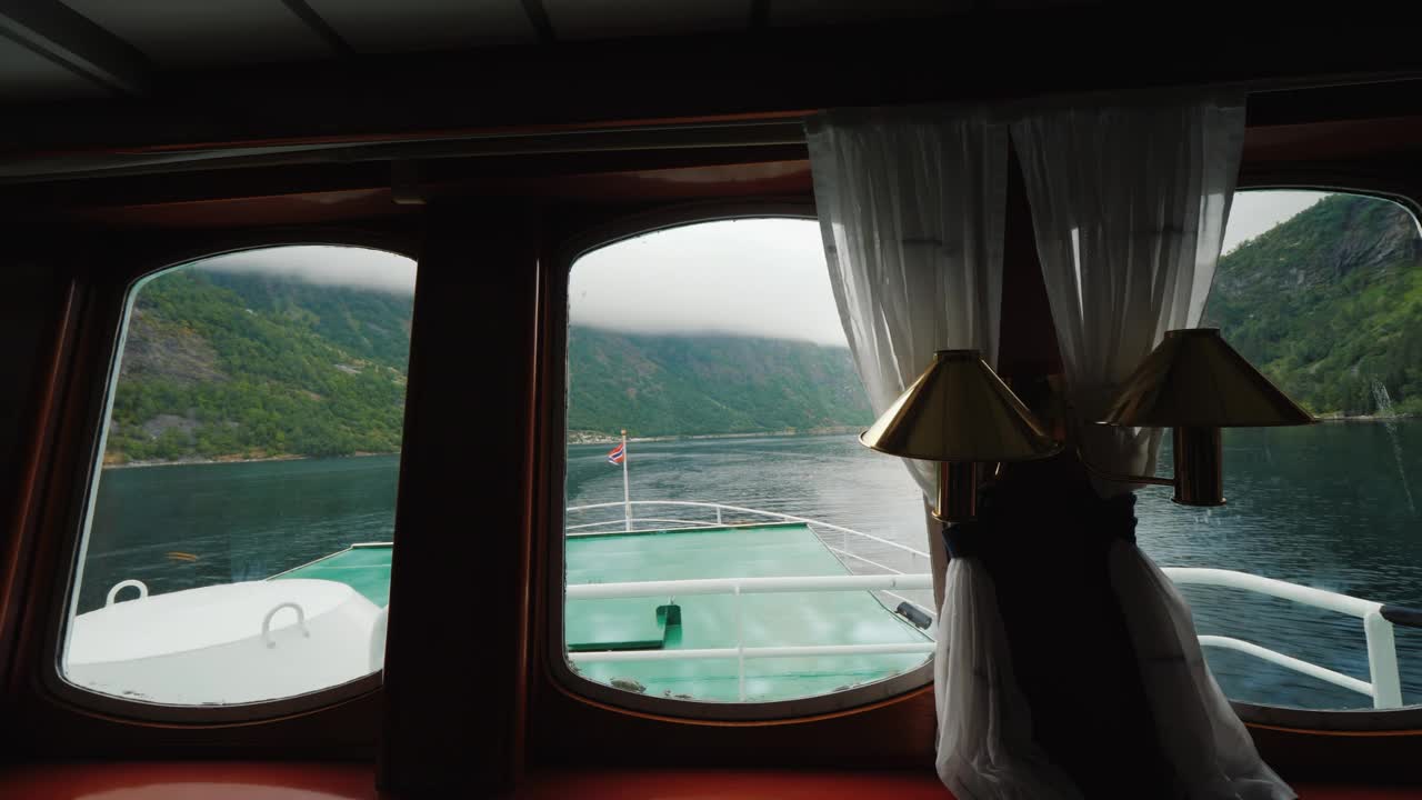 在风景如画的峡湾巡航-从船上的窗户看。可以看到一面挪威国旗视频下载