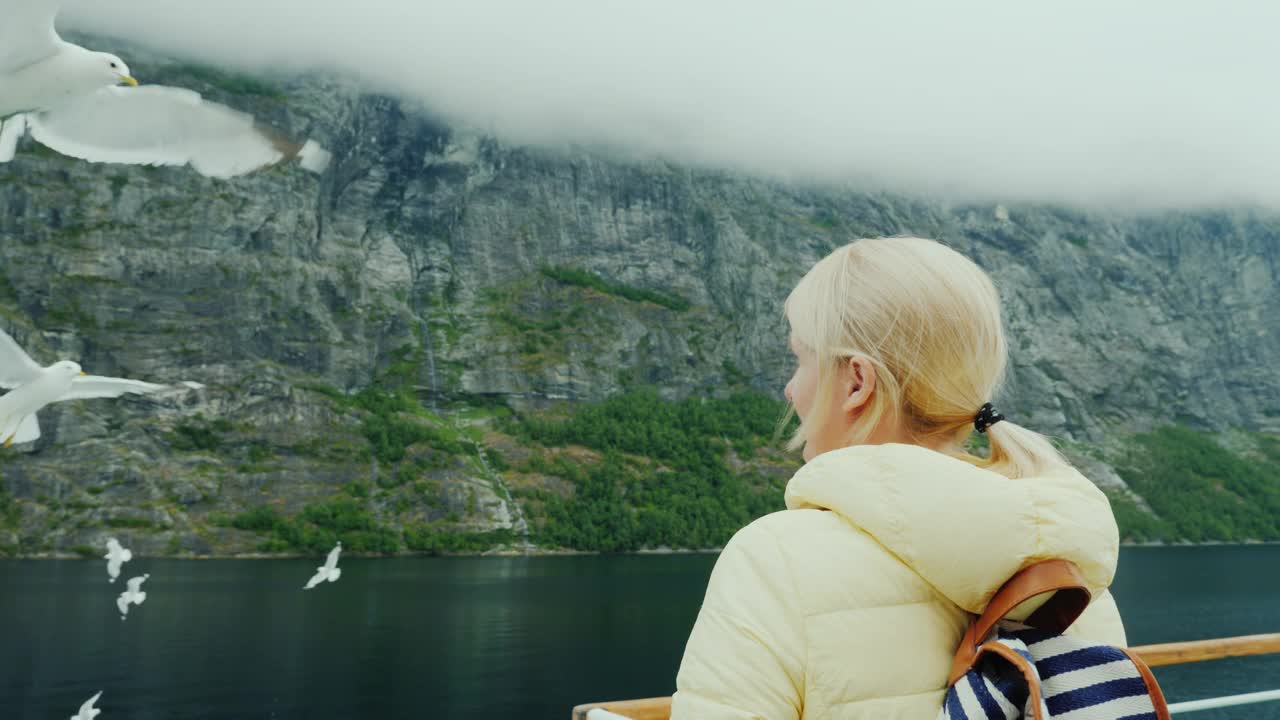 船上的一位妇女喂海鸥。挪威峡湾游船视频下载