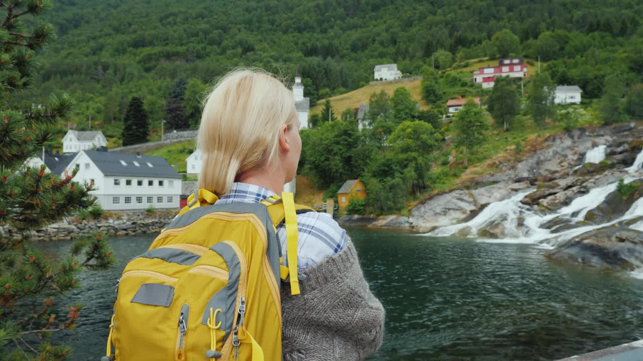 一位妇女欣赏挪威的村庄和瀑布。斯堪的纳维亚之旅视频下载