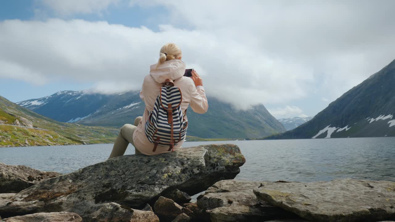 一位旅行者在挪威一个风景如画的高海拔湖泊拍照视频下载