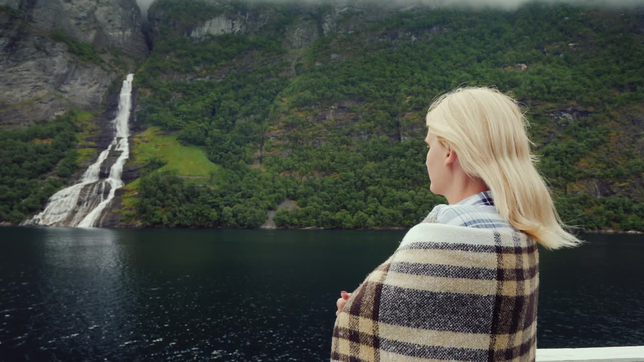 邮轮乘客欣赏着远处美丽的峡湾和瀑布。挪威邮轮视频下载