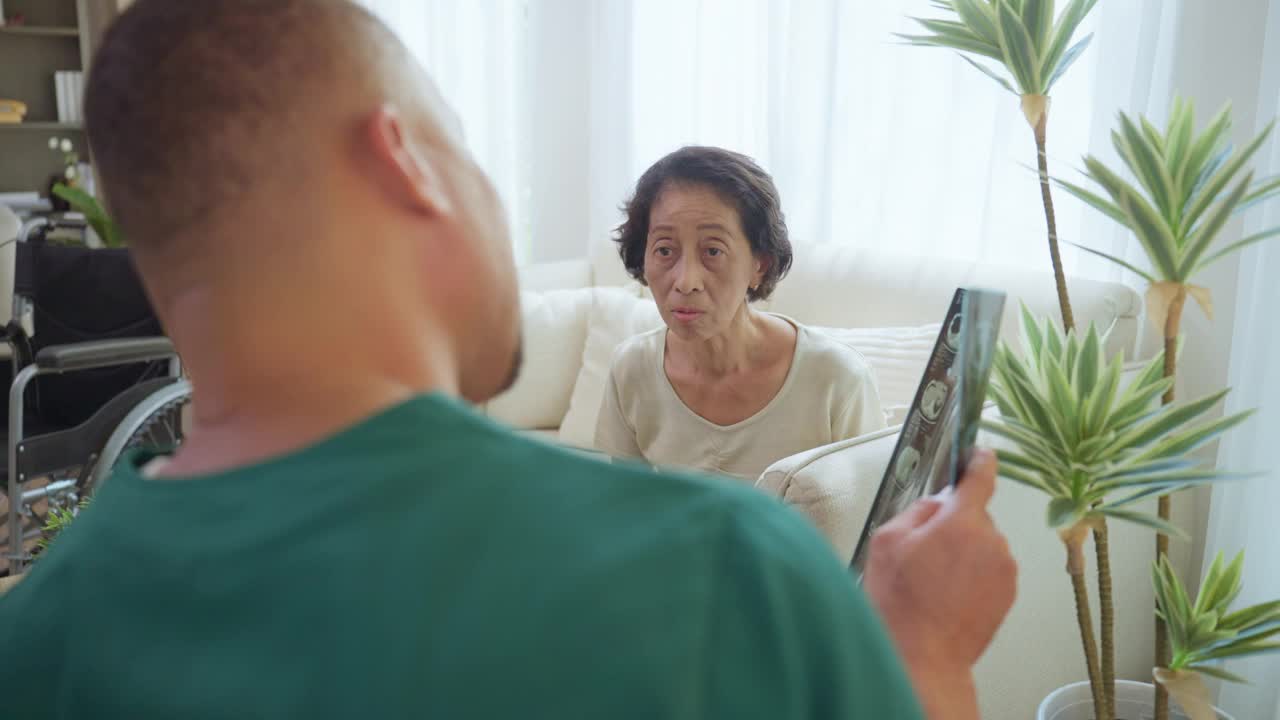 老年妇女专注地听男护士讲解体检的x线影像结果，对老年人的疾病预防进行医学调查。视频下载