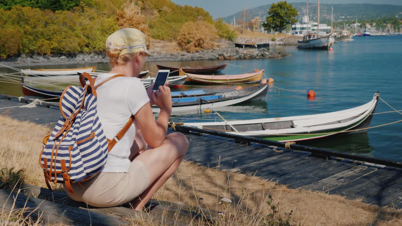 一个女人在海边休息，用智能手机眺望奥斯陆市的后视图视频下载