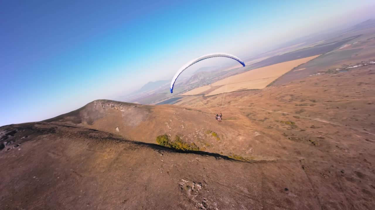 滑翔伞后面的鸟瞰图。FPV无人机追逐在机翼上进行危险动作的运动员视频下载