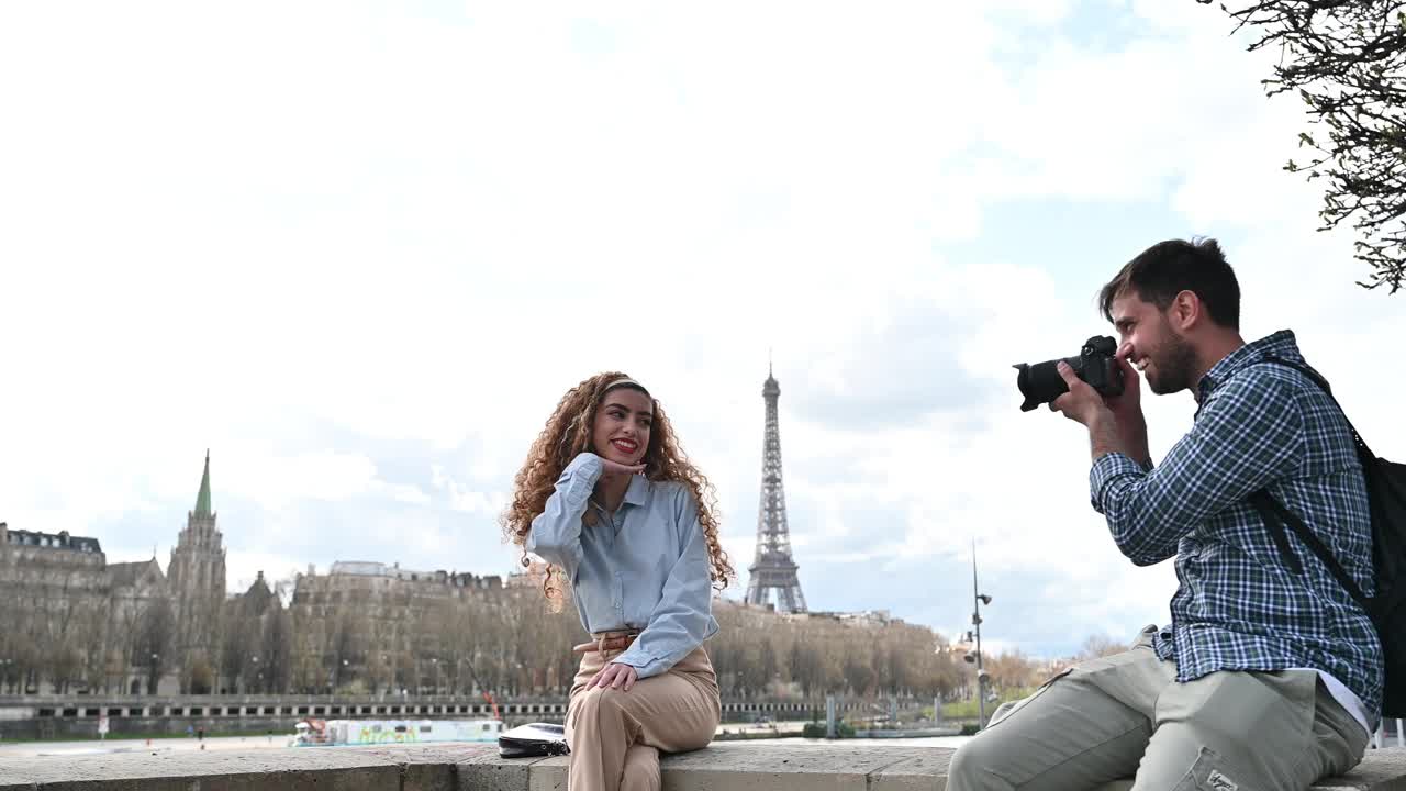 千禧一代夫妇在法国巴黎的地标附近拍照。千禧一代男子在埃菲尔铁塔前拍摄年轻女子视频素材