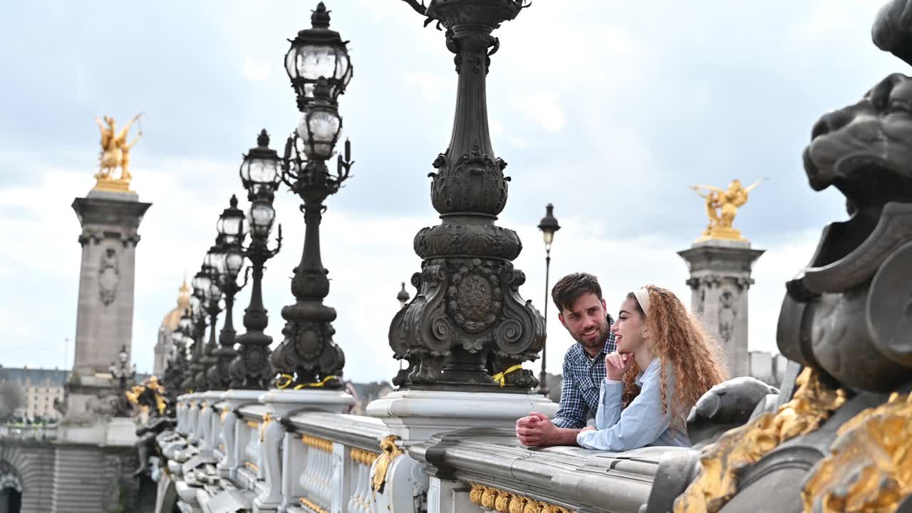 年轻的夫妇在城市的历史桥上欣赏风景。游客在巴黎参观地标视频下载
