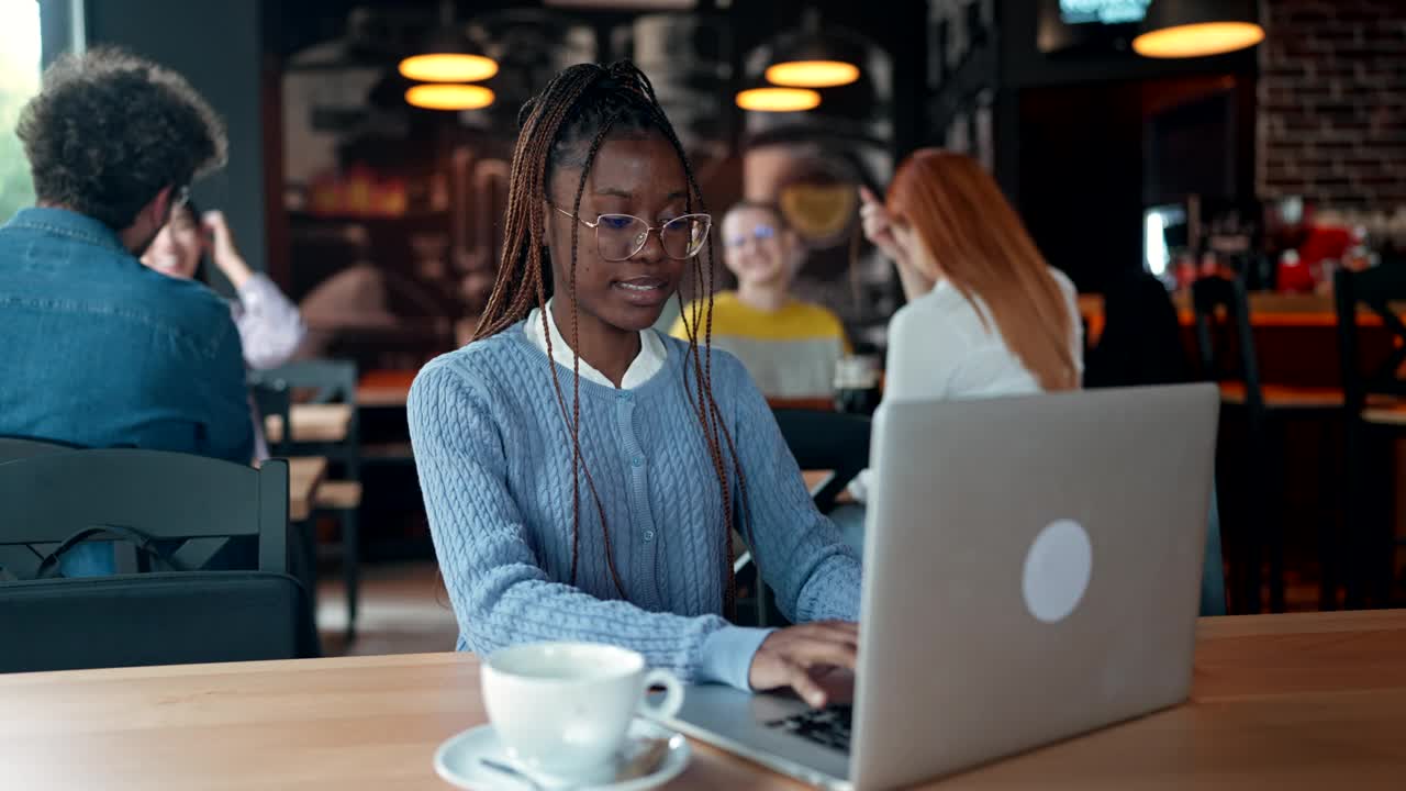 年轻的女商人在咖啡馆里使用笔记本电脑视频下载