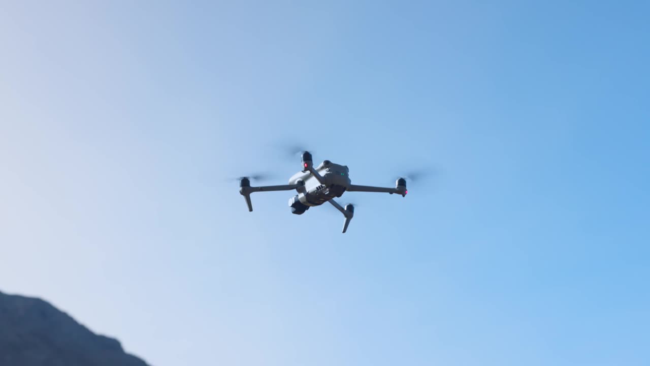 无人机降落在草地上，背景是山脉视频下载