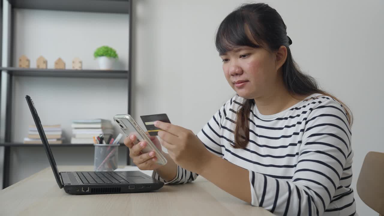女士在工作休息时间用信用卡使用智能手机移动购物视频下载