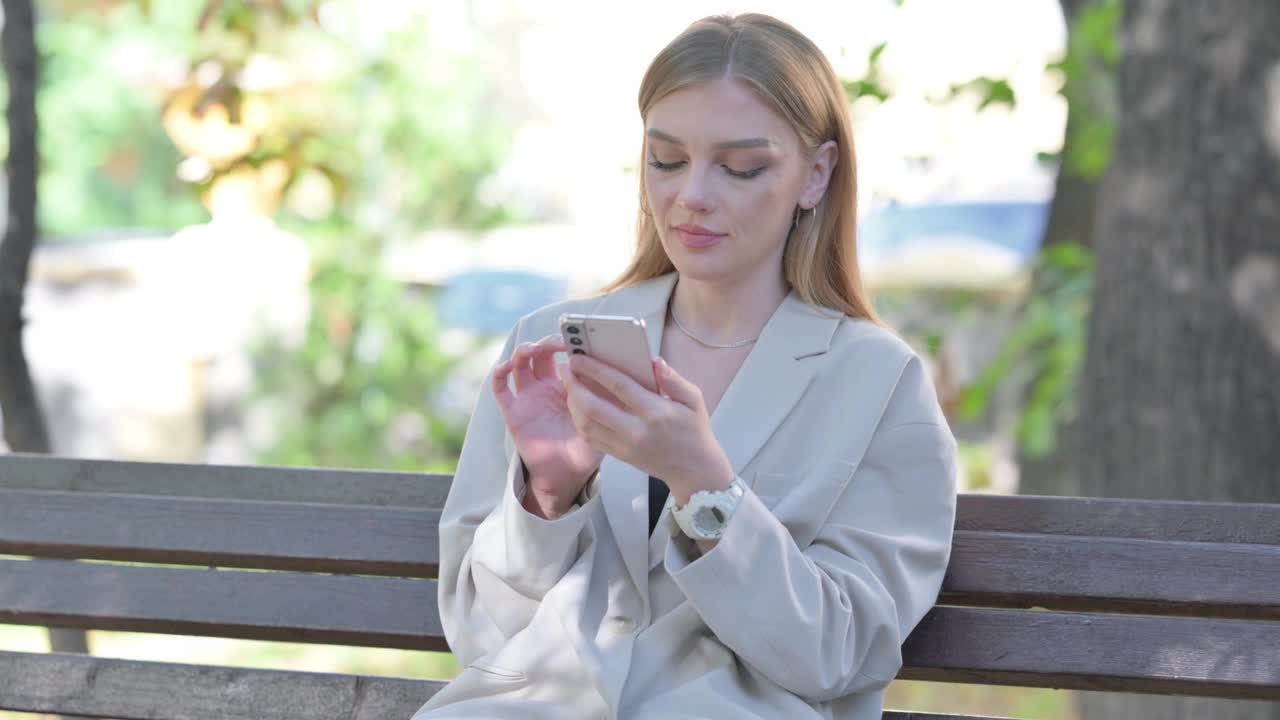 年轻的女商人坐在长凳上被电话的损失震惊了视频下载