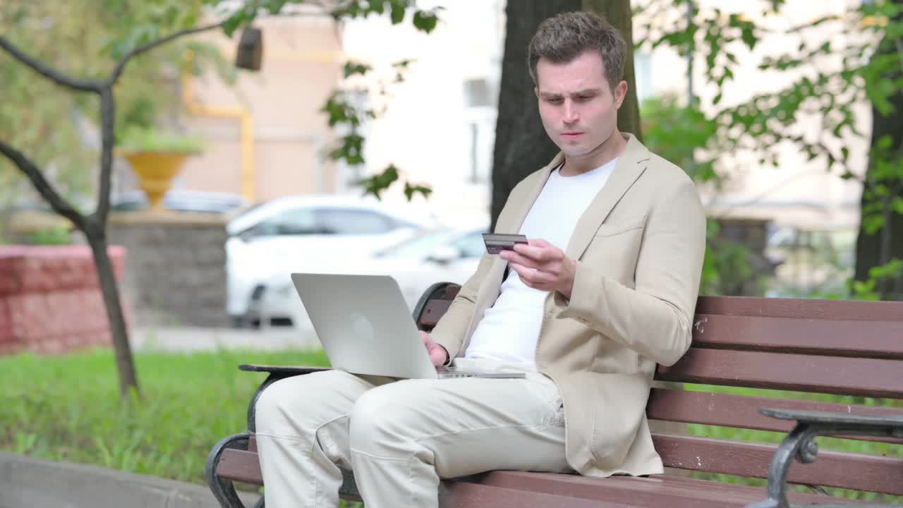 休闲的年轻人兴奋的成功网上购物的笔记本电脑户外视频下载