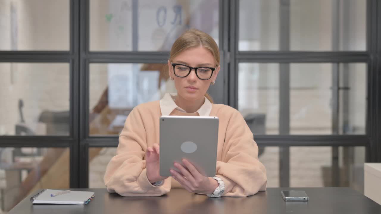 年轻女性在办公室使用数码平板电脑视频下载