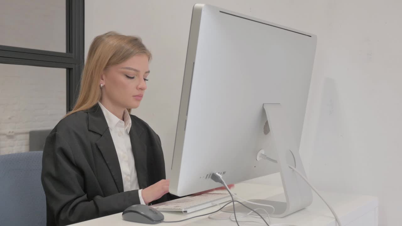 在办公室用电脑工作时看着相机的女商人视频下载