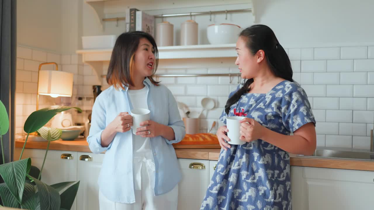 好老朋友回老家亚洲成熟女性朋友谈话站在厨房积极的谈话良好的关系友谊团聚家访随意放松手握咖啡杯在家里好气氛视频下载