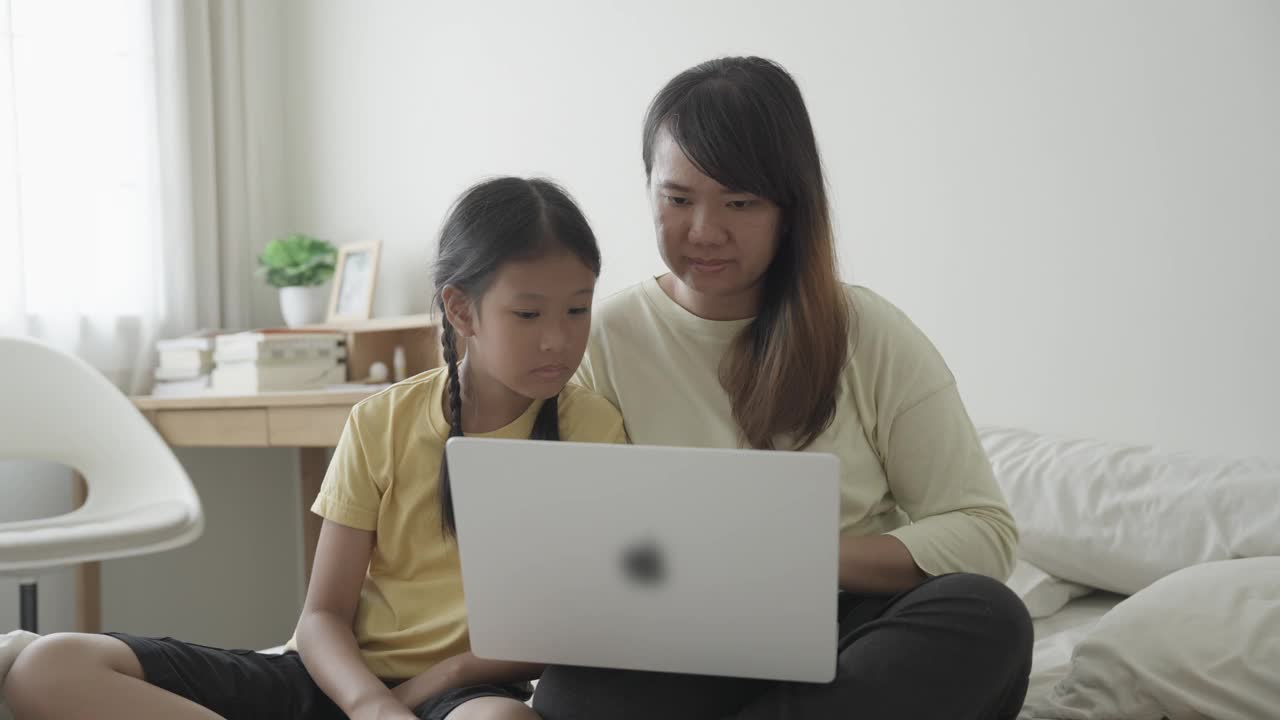 年轻女子和女儿一起使用笔记本电脑视频下载