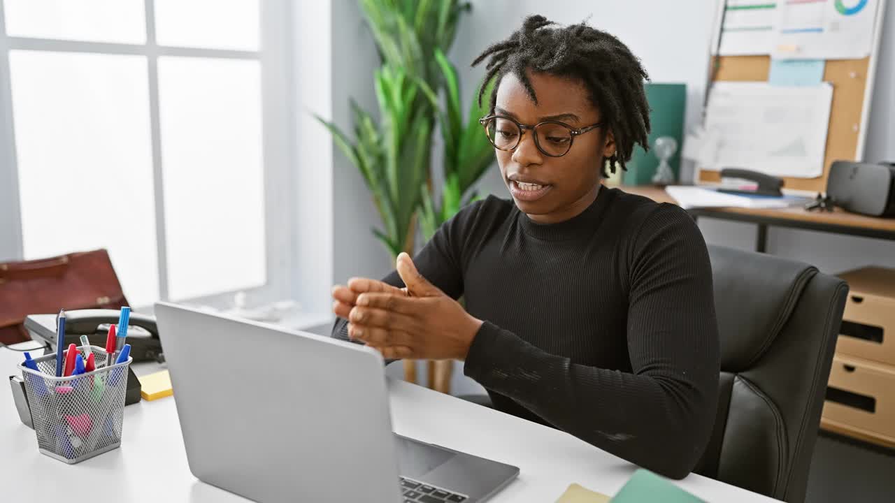 留着脏辫的非裔美国女性在现代办公环境下用笔记本电脑工作。视频下载