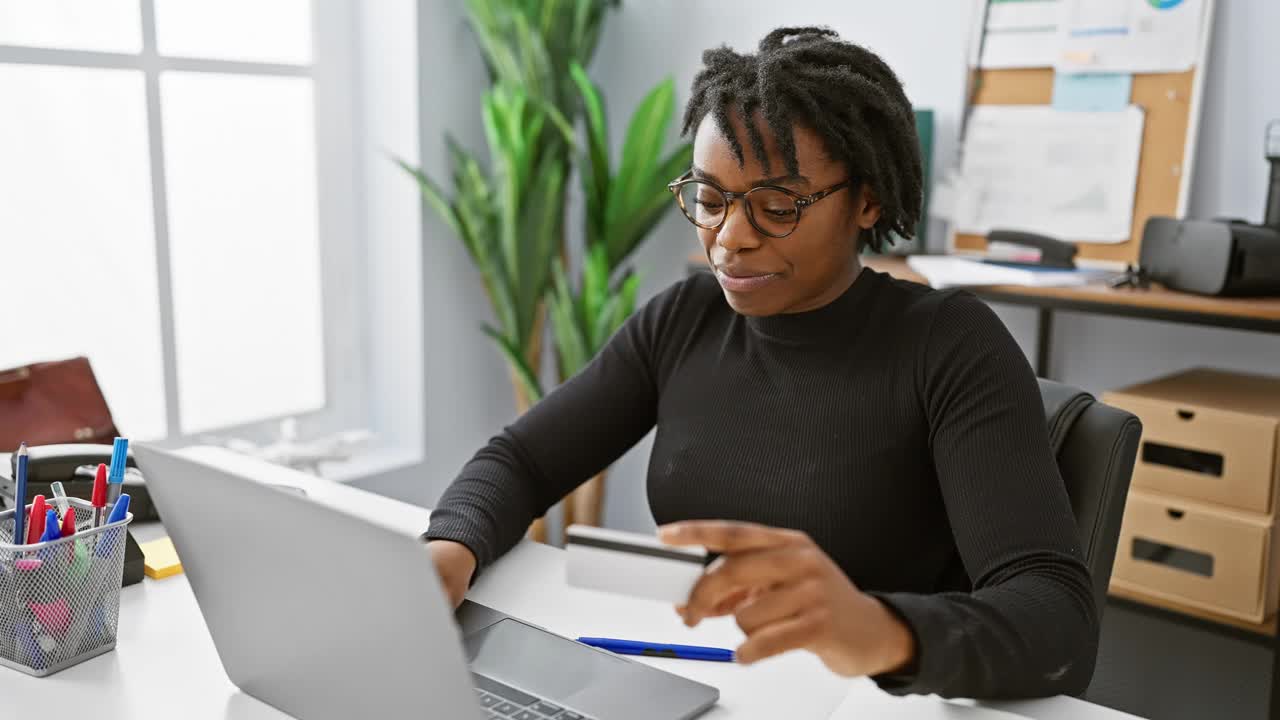 留着脏辫的非裔美国妇女在现代办公环境中使用电脑。视频下载