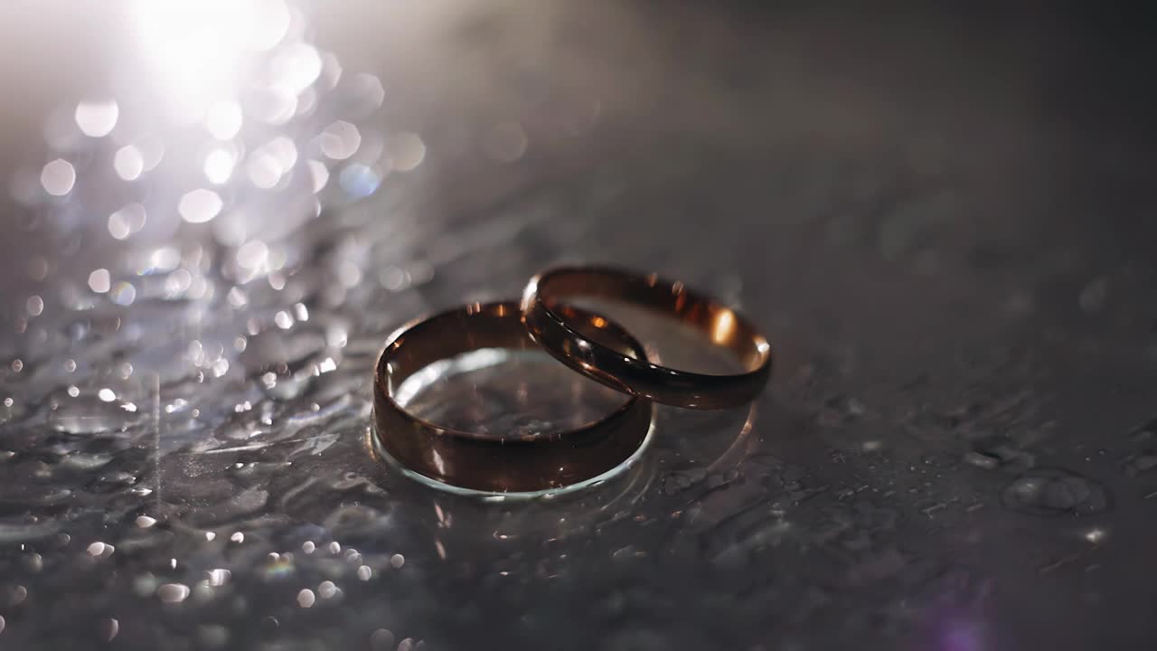 两个金戒指被一道美丽的光照亮。他们一个接一个地躺在桌子上视频下载