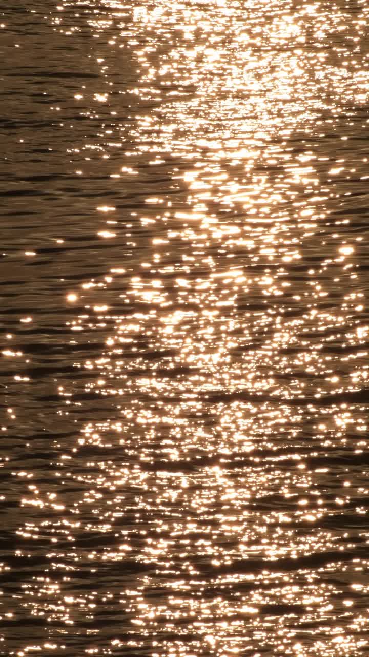 日落时金色的海浪。4 k垂直视频下载