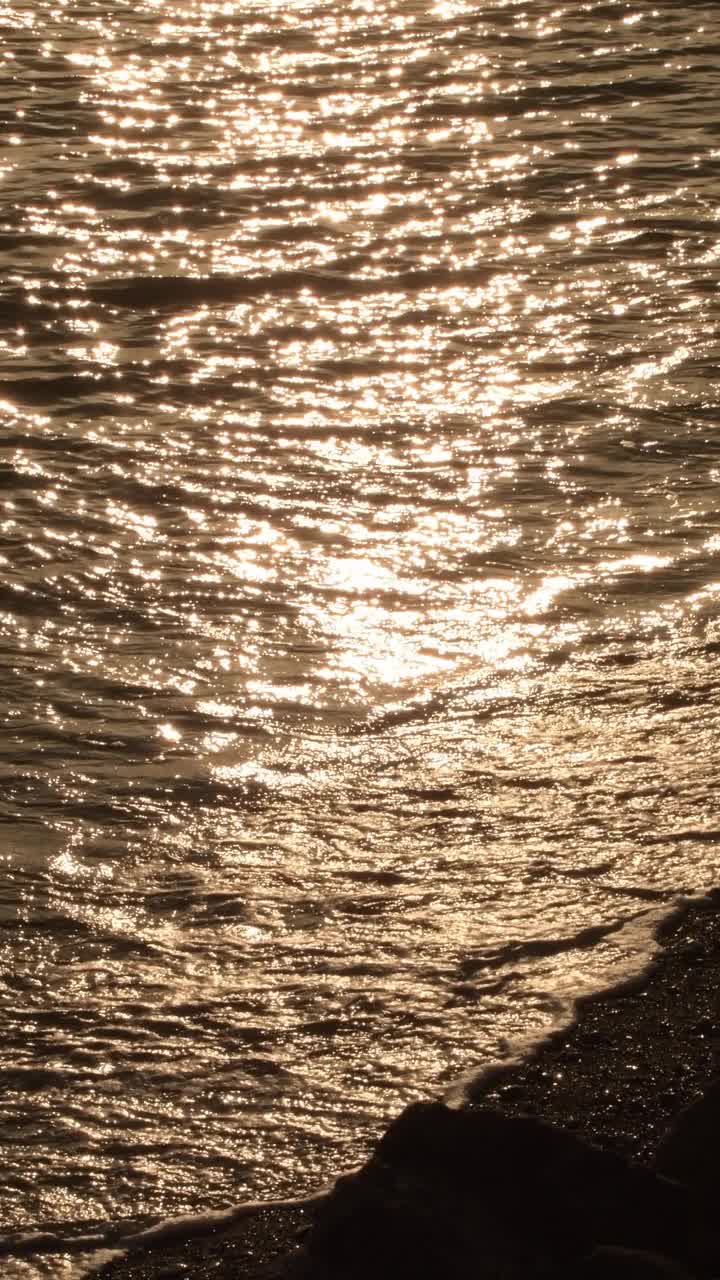 日落时海边金色的波浪。4 k垂直视频素材