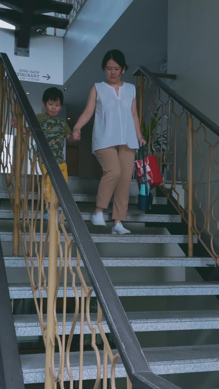在热带度假胜地的操场上，母亲牵着儿子去玩耍。视频下载