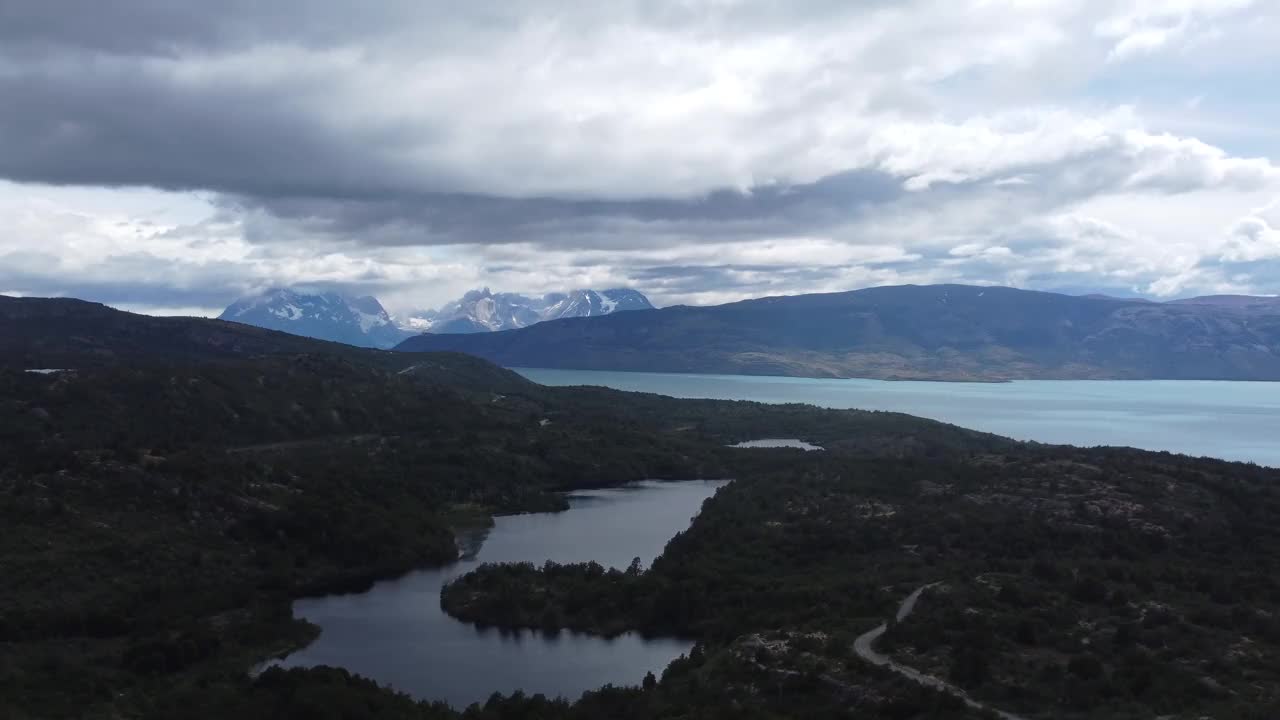 镜头从远处的湖泊和白雪皑皑的山脉横向移动到智利的托雷斯德尔潘恩国家公园视频下载