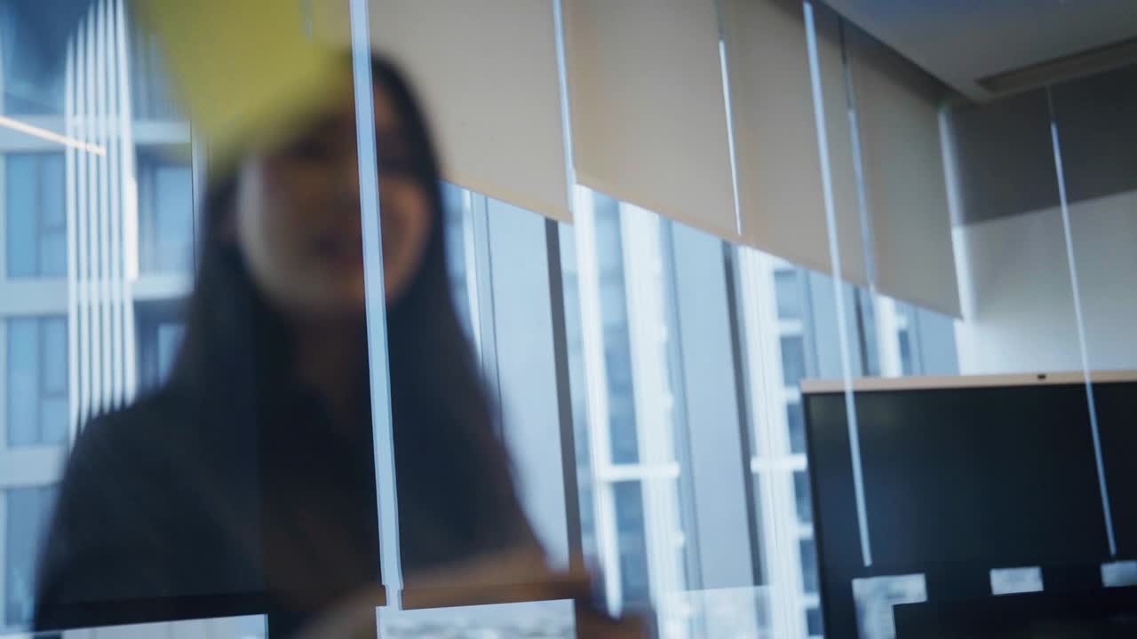 亚洲女性在玻璃上留言，在会议室与同事聊天视频下载