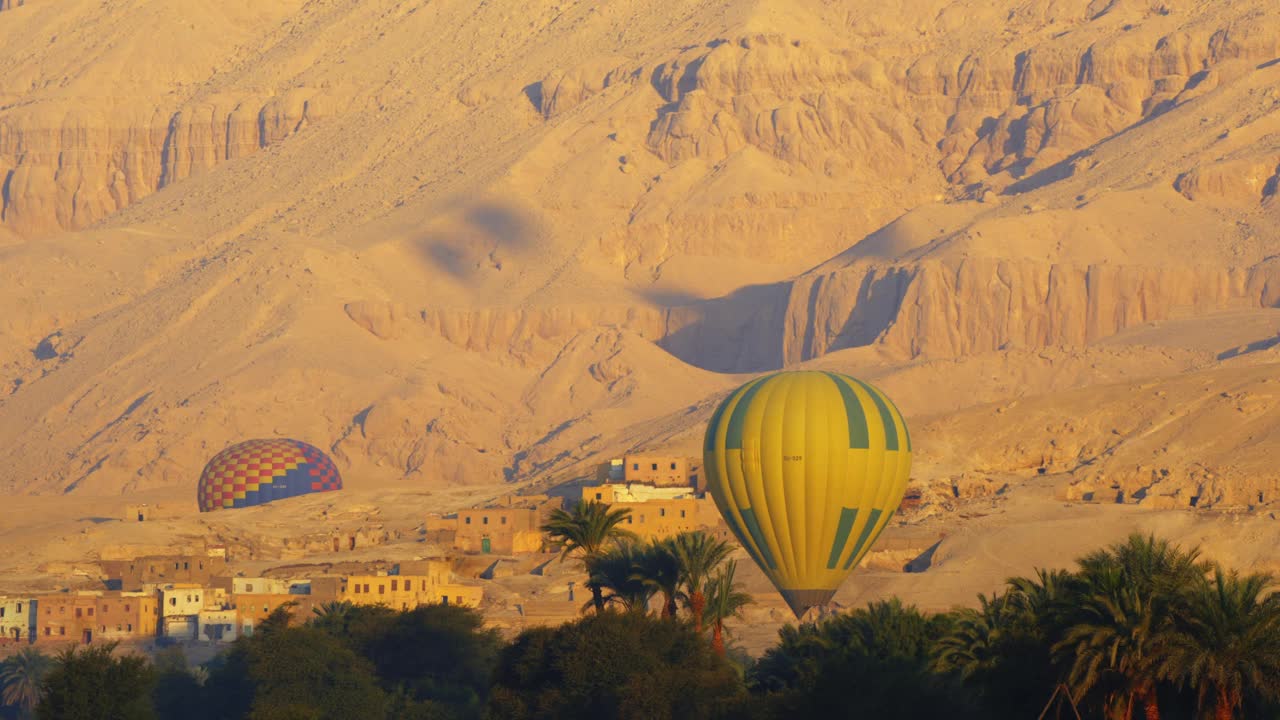 黎明时分，埃及尼罗河谷卢克索，天空中有热气球的门农巨像。视频下载