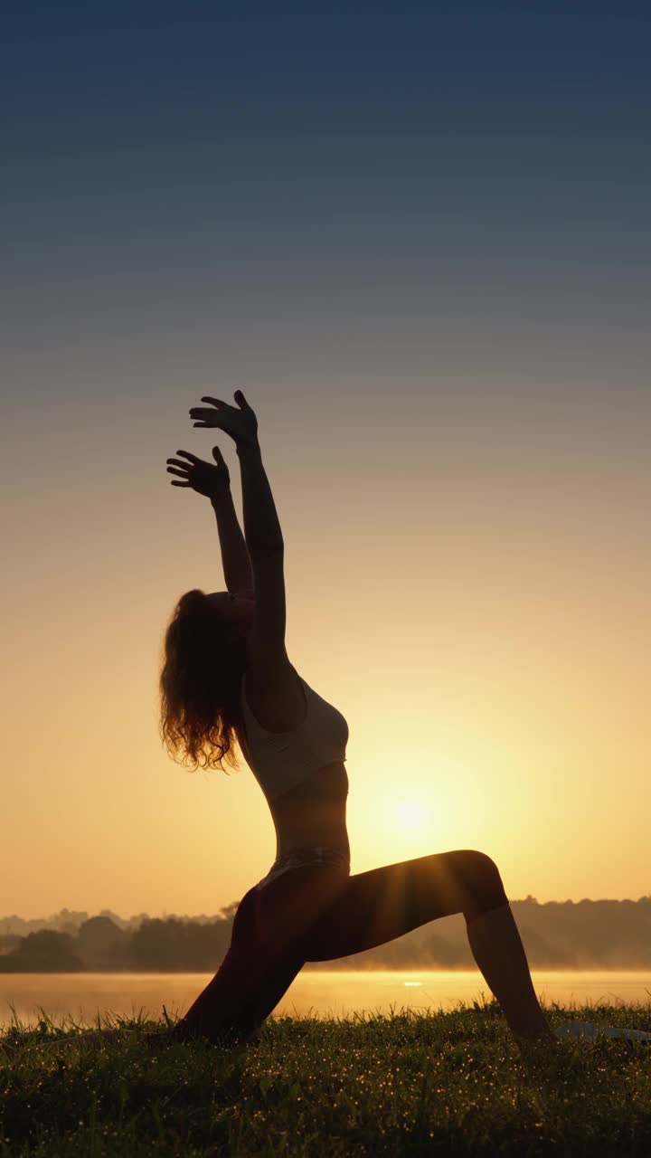 高镜头:年轻的女运动员在做瑜伽，保持一个姿势，专注于她的健康。视频下载