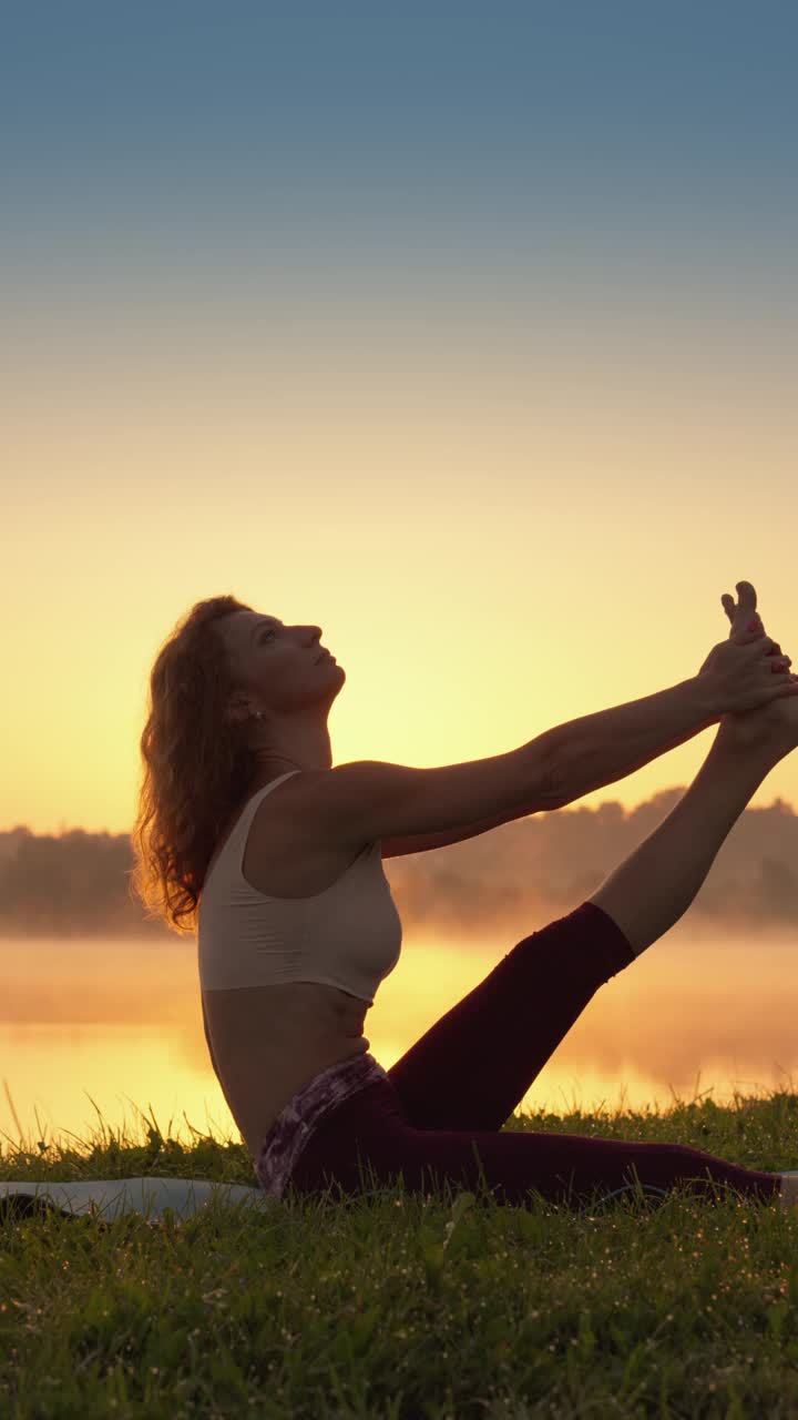 在湖边，一名女子练习瑜伽，这有助于她放松身心，同时沉浸在自然环境中，感受平静和内心的平静。视频下载