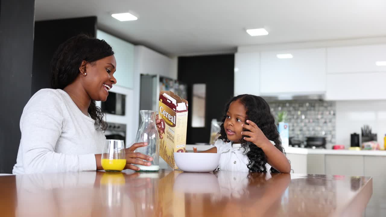 黑人女孩在妈妈的监督下在家里做麦片早餐视频下载