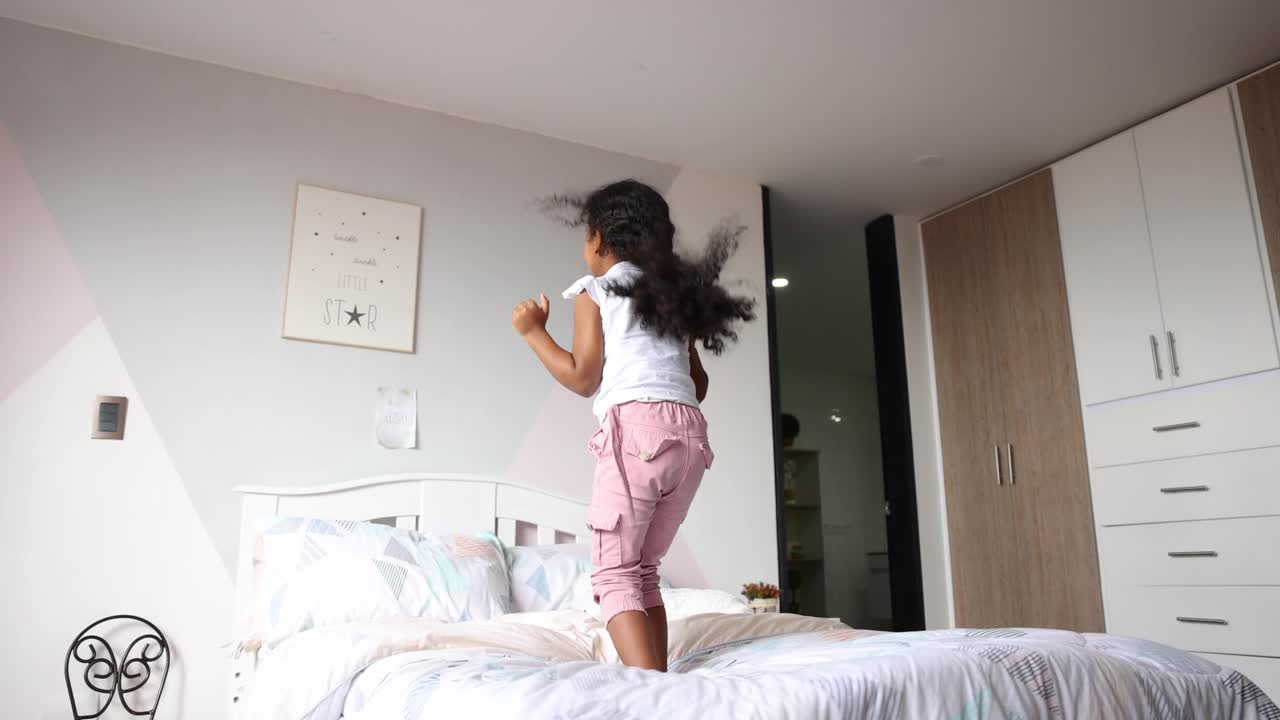 快乐的女孩在家里的床上蹦蹦跳跳视频下载