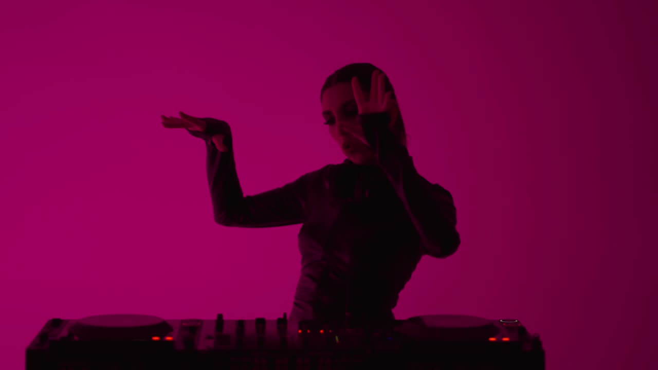 美丽的黑发女子站在现代DJ控制器，女DJ玩电子音乐视频下载