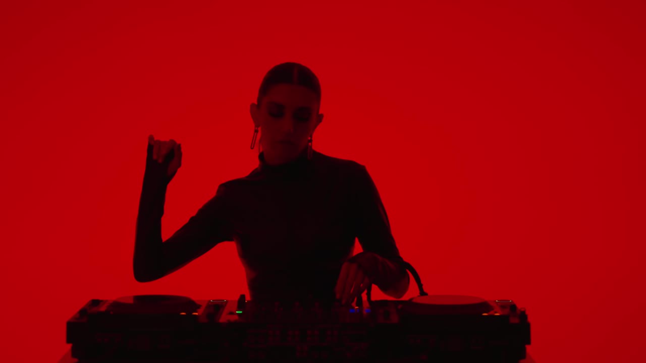 性感女士DJ混合电子轨道在工作室与红色背景，中等肖像拍摄视频下载