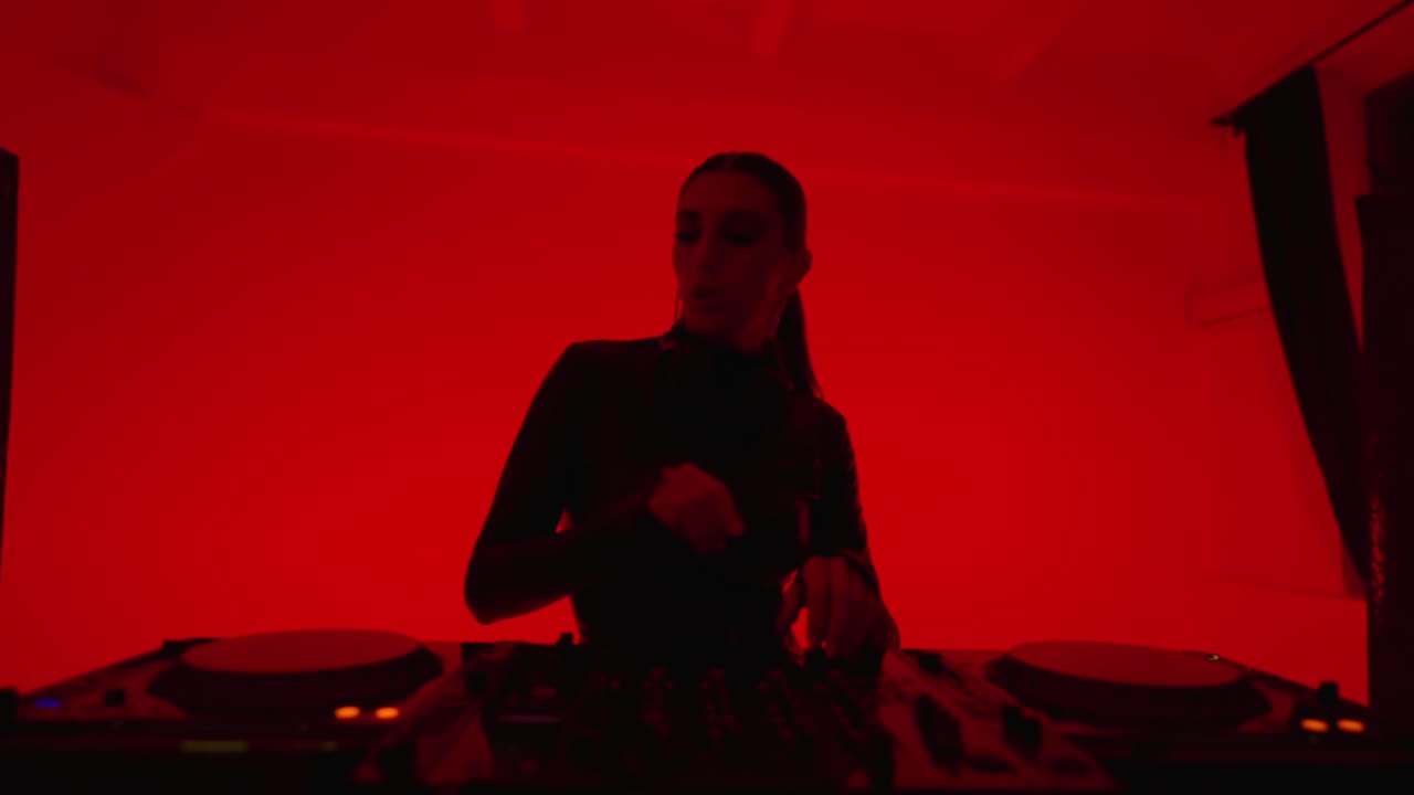 性感女人DJ玩电子音乐在工作室与红色背景，中等肖像视频下载