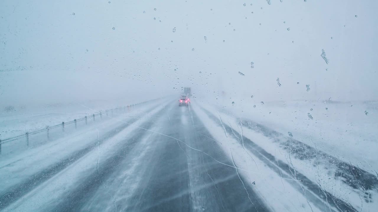 冰岛乡村，暴风雪和大风天气下，汽车行驶在积雪覆盖的公路上，能见度很低视频下载