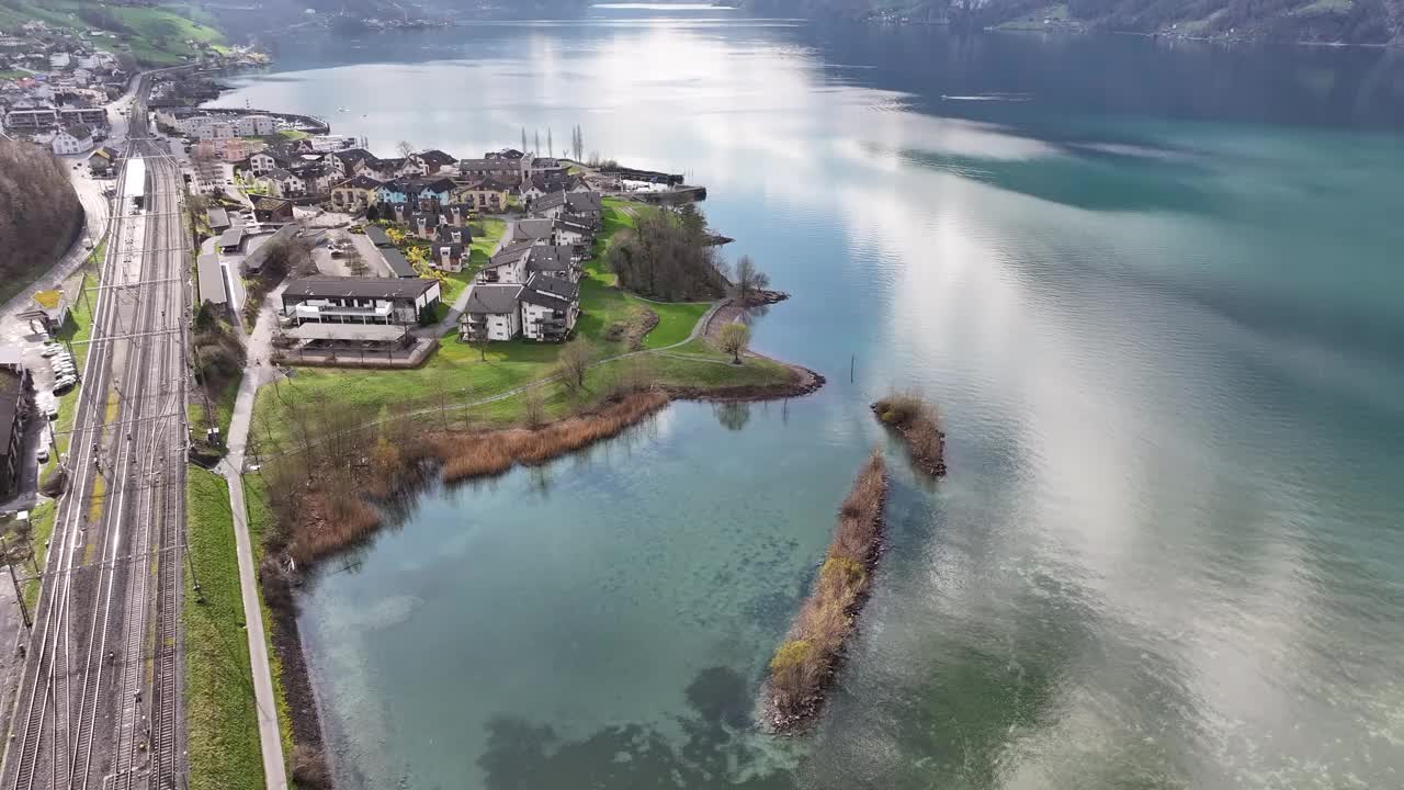 坐落在瑞士瓦伦塞湖畔的住宅区沿着海岸线延伸，铁路蜿蜒穿过古色古香的穆格村庄。视频素材