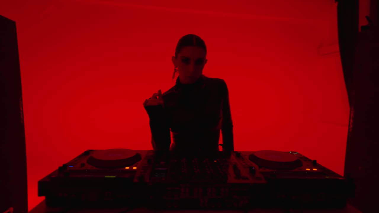 时尚的女DJ跳舞和播放电子音乐的夜总会与红灯，肖像视频下载
