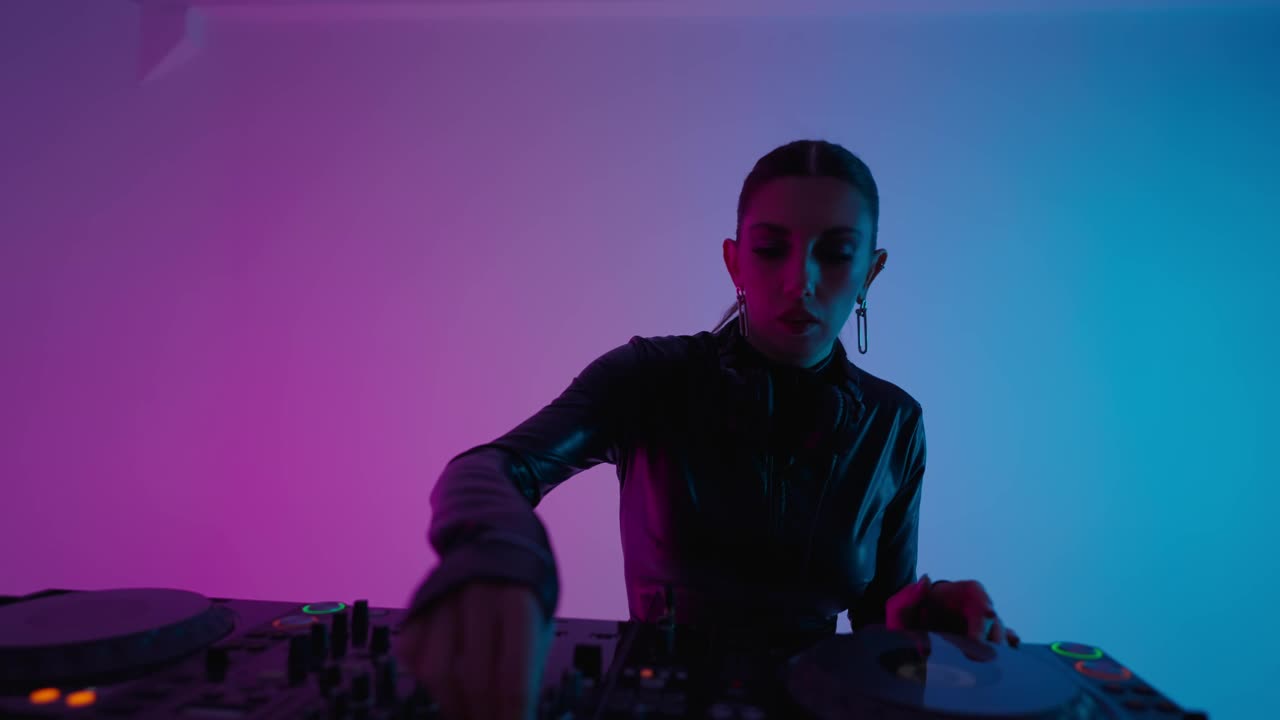 性感女士DJ在录音室播放电子音乐，红色的灯光，美女的中等肖像视频下载