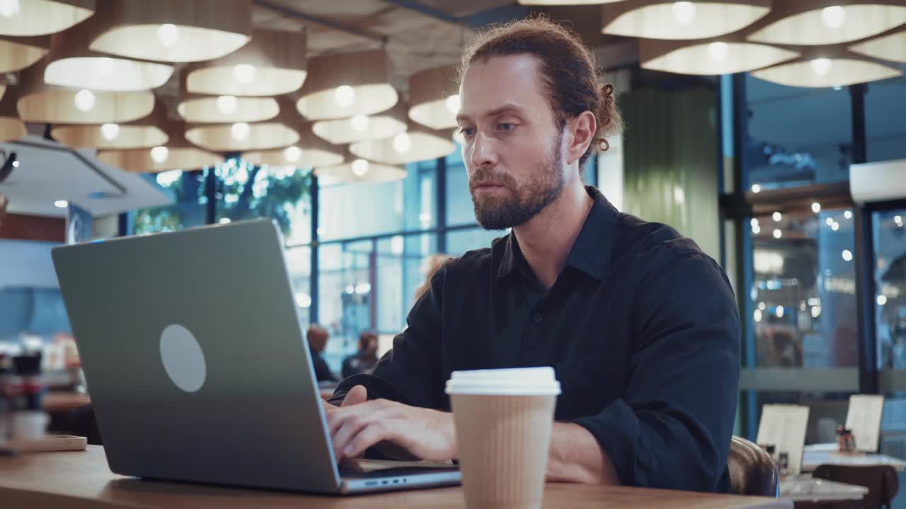 一个全神贯注的人坐在咖啡店里，用笔记本电脑提高数字技能。数字的技能。自由职业者使用计算机有效执行任务所需的一套技术能力。视频下载