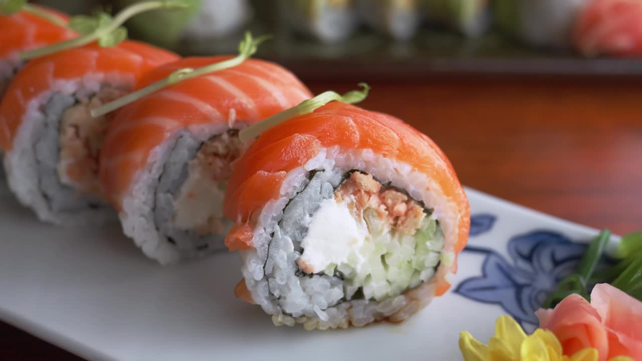 餐厅餐桌上美味佳肴的特写镜头，以寿司为焦点。日本料理的世界，近距离观看寿司卷在餐厅的桌子上。装在白色盘子里的寿司卷视频下载