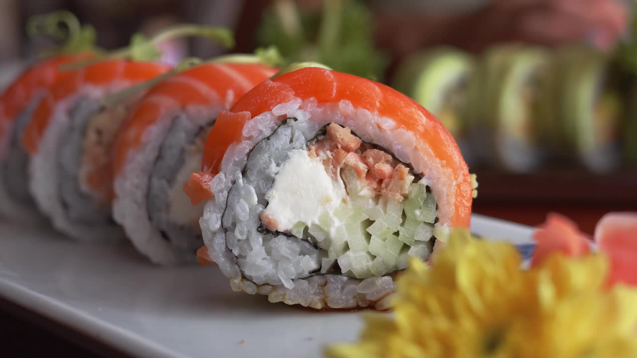 近距离拍摄寿司卷，在餐厅里盛在盘子里。传统的日本寿司。美味的加州寿司卷配鲑鱼。视频下载