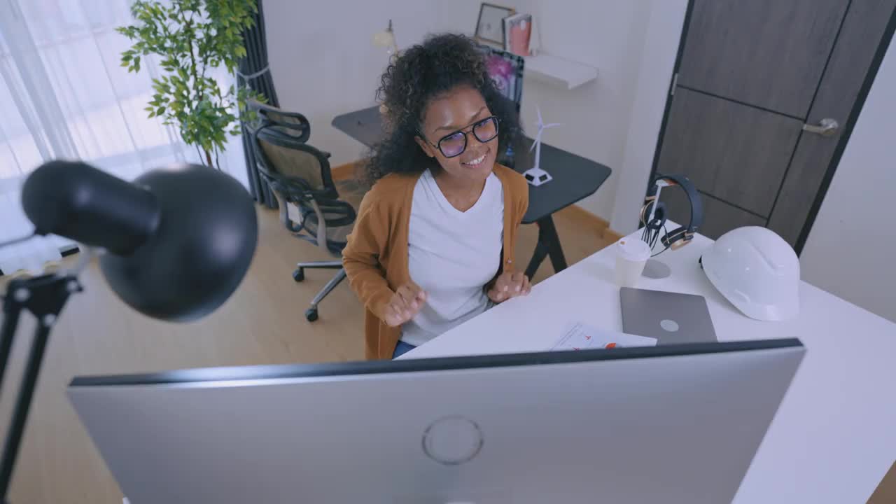 一头非洲发型的自信女商人在办公桌前使用电脑。女企业家在家工作。她在远程办公。视频下载