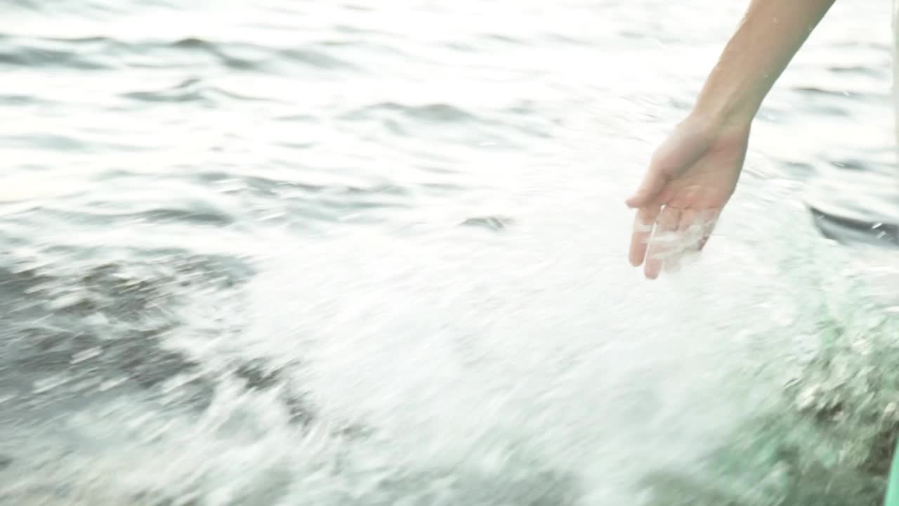 日落时，特写一个女孩的手在水中移动视频下载