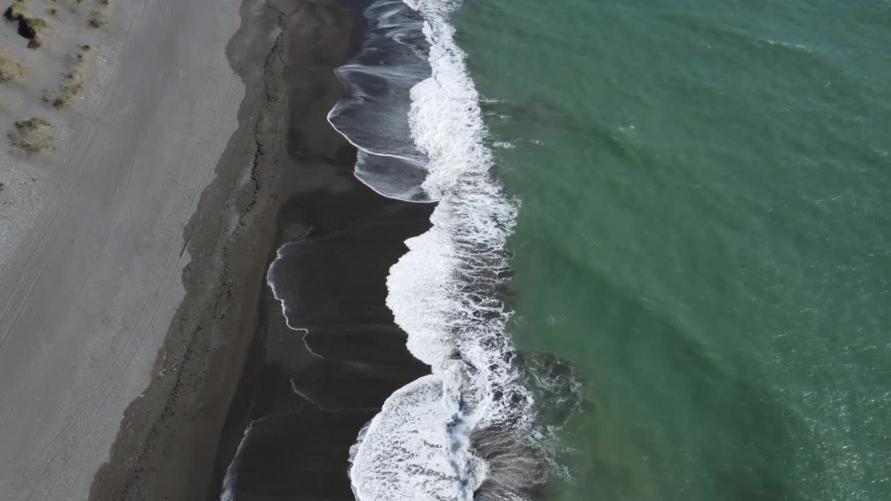 海浪拍打着黑色的海滩，深绿色的海洋摄像机沿着海滩移动视频下载