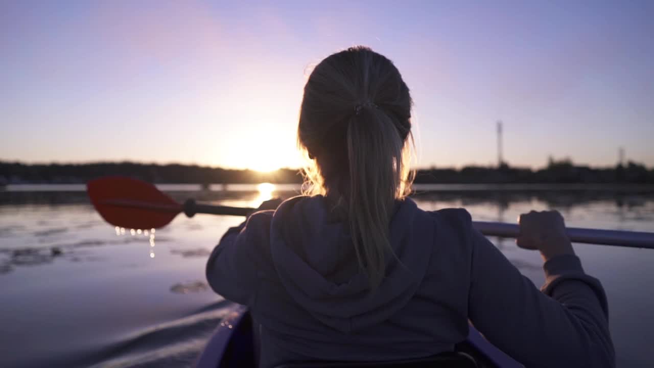 女子在夕阳的映衬下划着皮艇航行视频下载