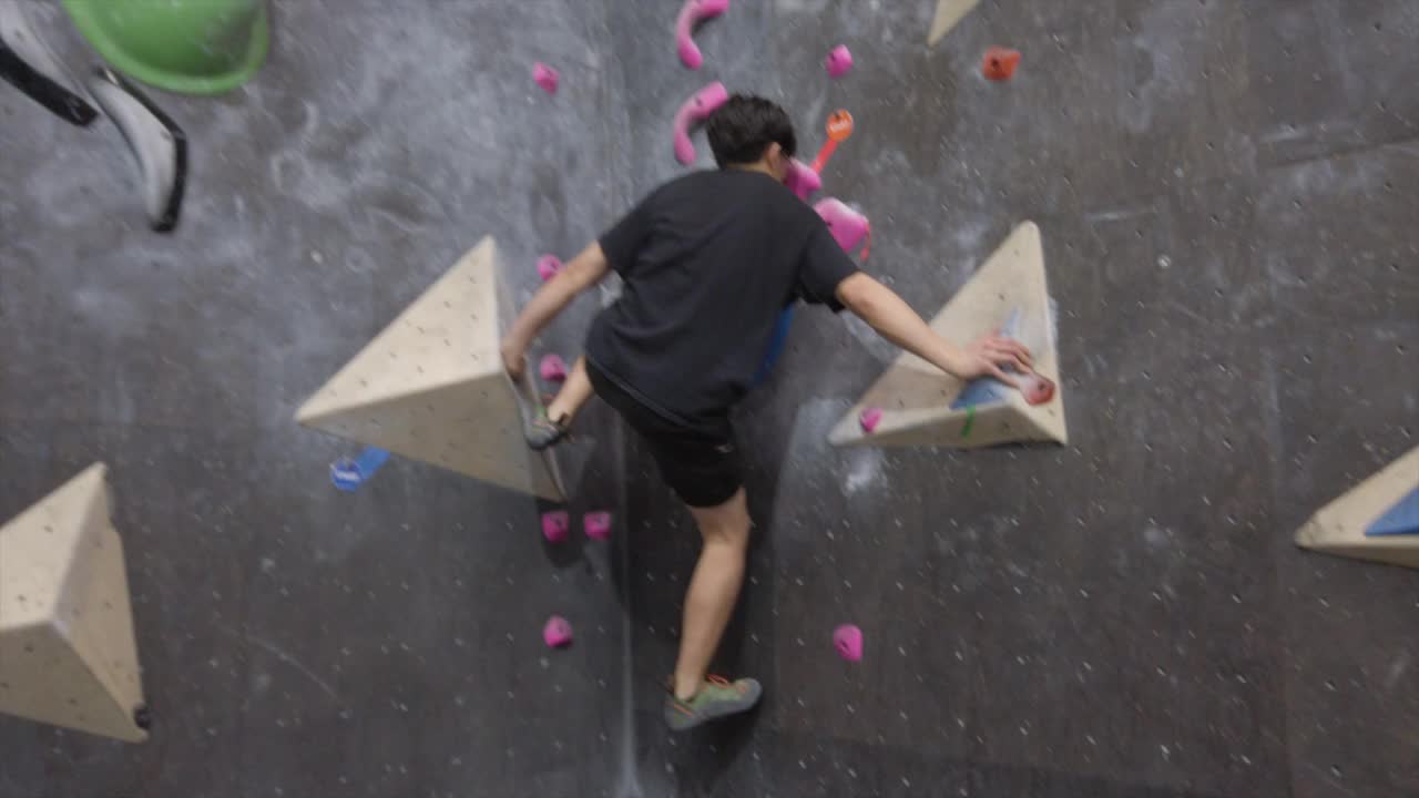 亚洲攀岩者在健身房攀爬室外抱石墙。有趣的室内运动活动。视频下载