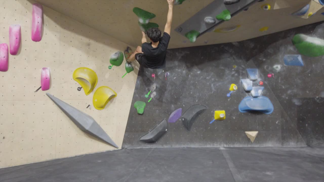 亚洲攀岩者在健身房攀爬室外抱石墙。有趣的室内运动活动。视频下载